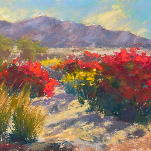Colorful bushes with red and yellow flowers bloom along a sunlit desert path, with mountains and trees in the background under a bright blue sky. The scene is painted with vibrant, textured brushstrokes. 15th Annual PleinAir Salon Art Competition