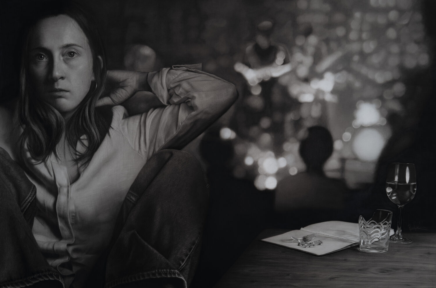 A woman sits with her knees up, looking serious, while a blurred band plays on stage in the background. A table holds a notepad, pen, a glass of water, and a glass of wine. 15th Annual PleinAir Salon Art Competition