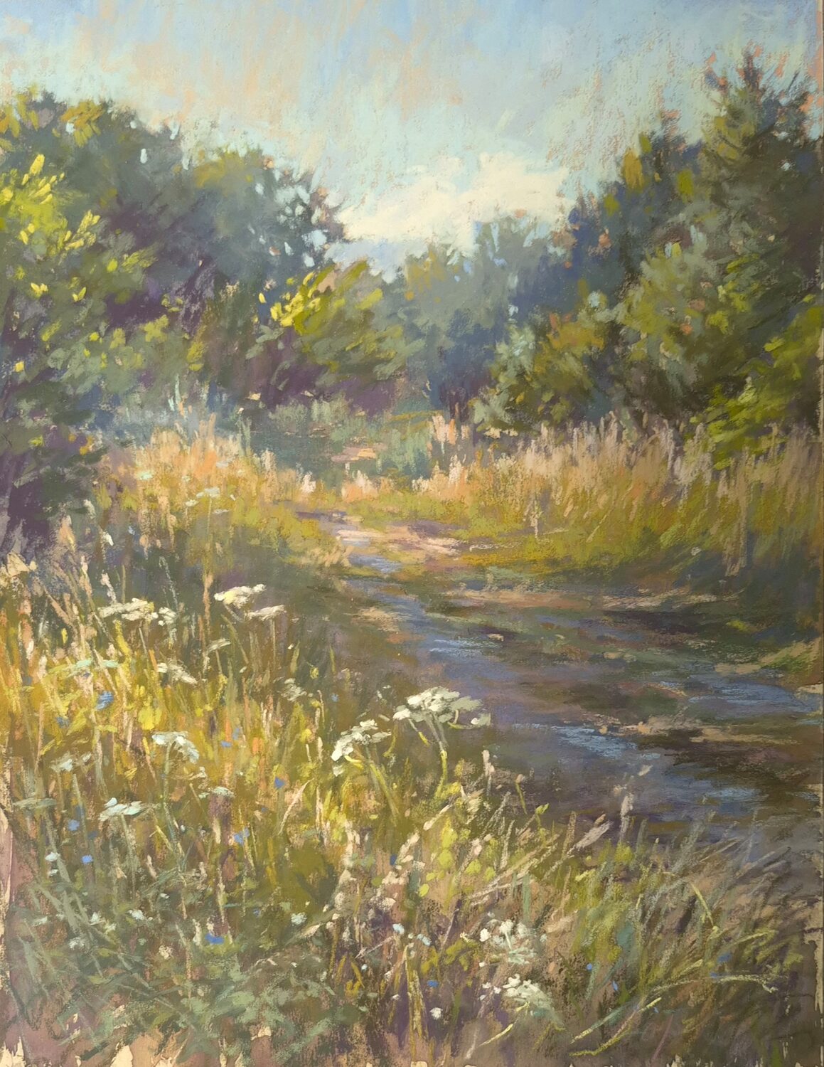 A sunlit dirt path winds through tall grasses and wildflowers, bordered by green trees under a bright blue sky with soft clouds. 15th Annual PleinAir Salon Art Competition