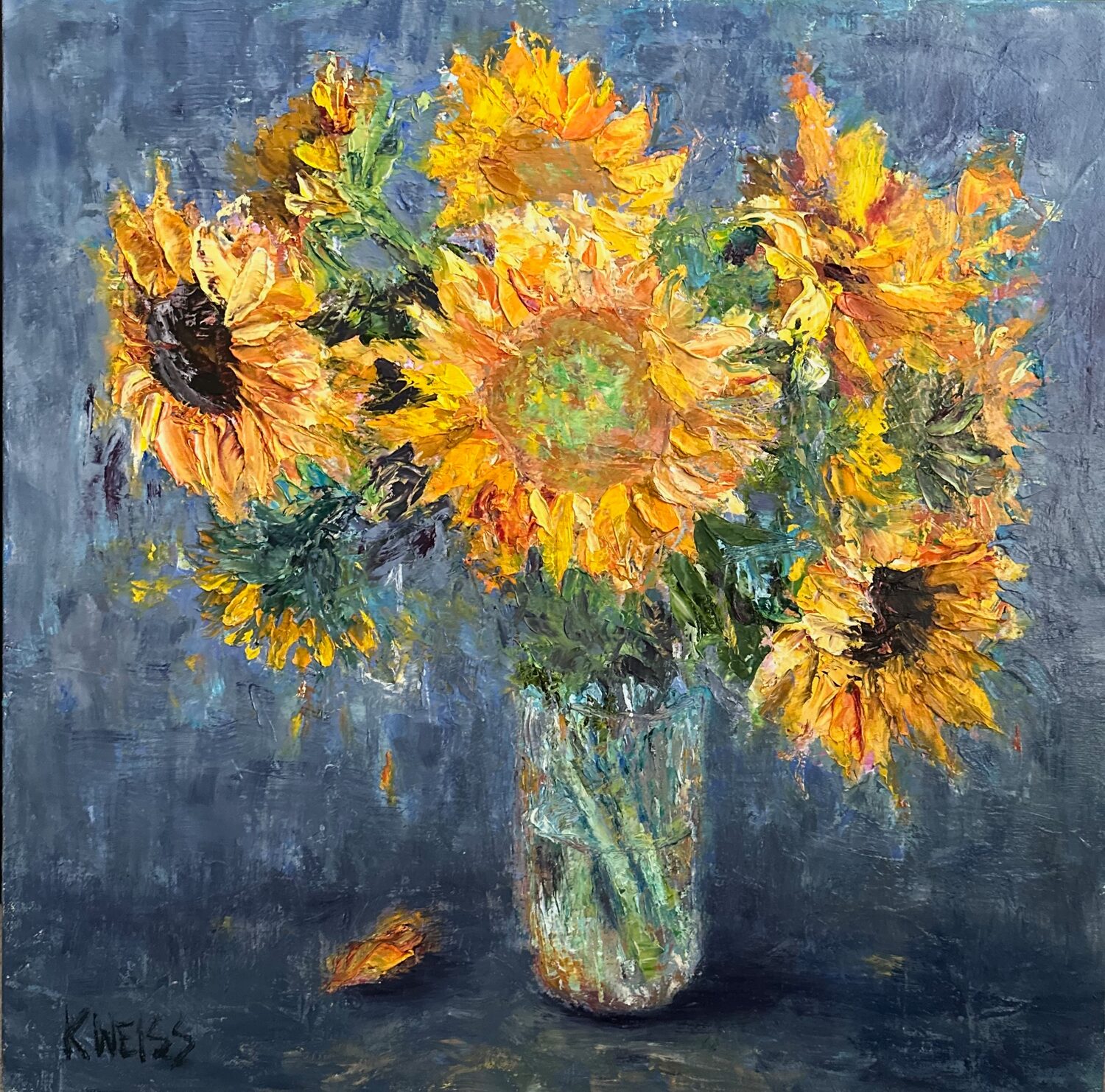 A vibrant painting of sunflowers in a glass vase against a blue background. The bright yellow petals contrast with the dark centers, and one fallen petal rests on the surface below. The signature KWEISS appears in the lower left corner. 15th Annual PleinAir Salon Art Competition