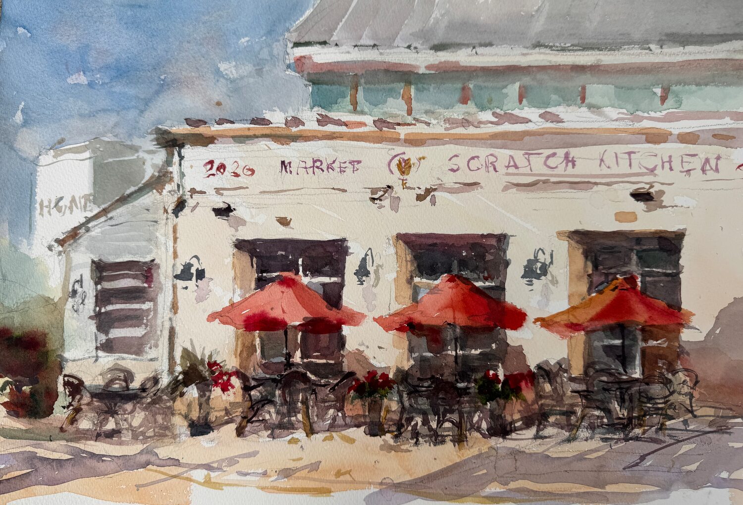 Watercolor painting of a café with three red umbrellas over outdoor tables and chairs, potted plants, and the sign Scratch Kitchen on the buildings facade under a blue sky. 15th Annual PleinAir Salon Art Competition