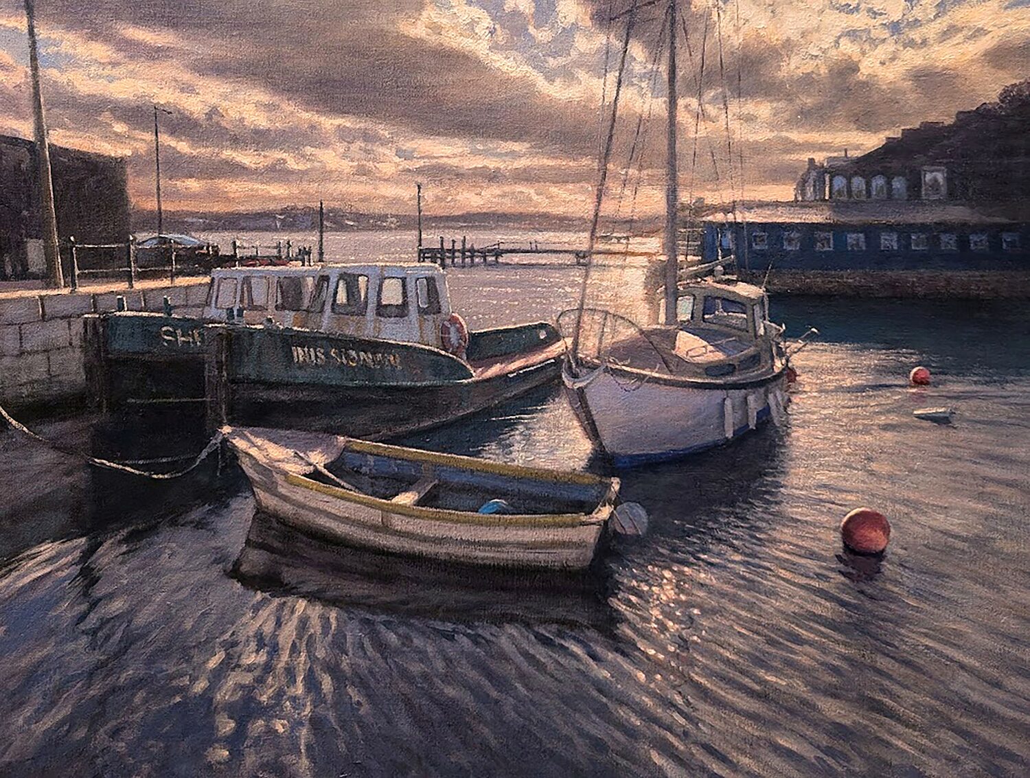 Three boats float in a harbor at sunset, with calm water reflecting light. A few red buoys drift nearby. Buildings and a dock line the shore under a partly cloudy sky with orange and purple hues. 15th Annual PleinAir Salon Art Competition