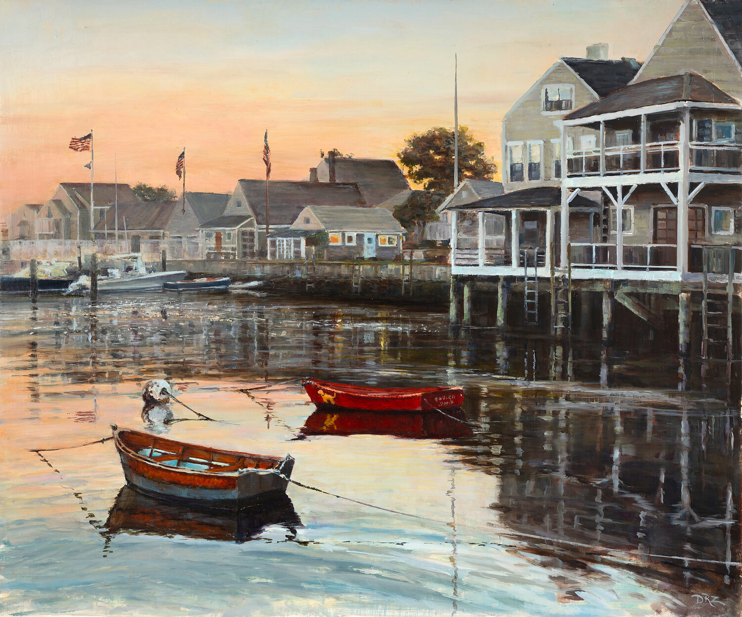 Two small boats float on calm water at sunset near wooden houses on stilts, with American flags visible and reflections shimmering in the harbor. 15th Annual PleinAir Salon Art Competition
